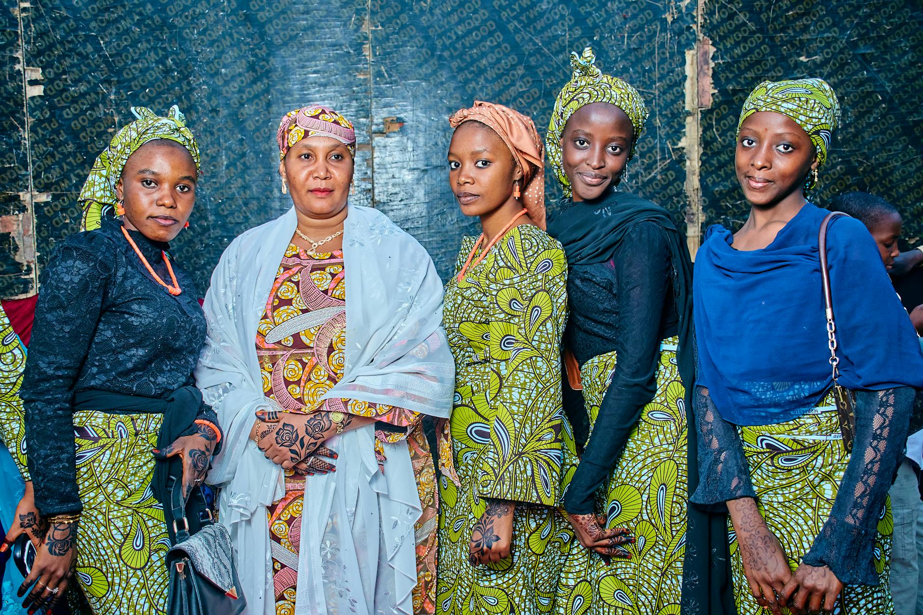Pięć kobiet w tradycyjnych strojach prezentuje kolorowe, etniczne wzory