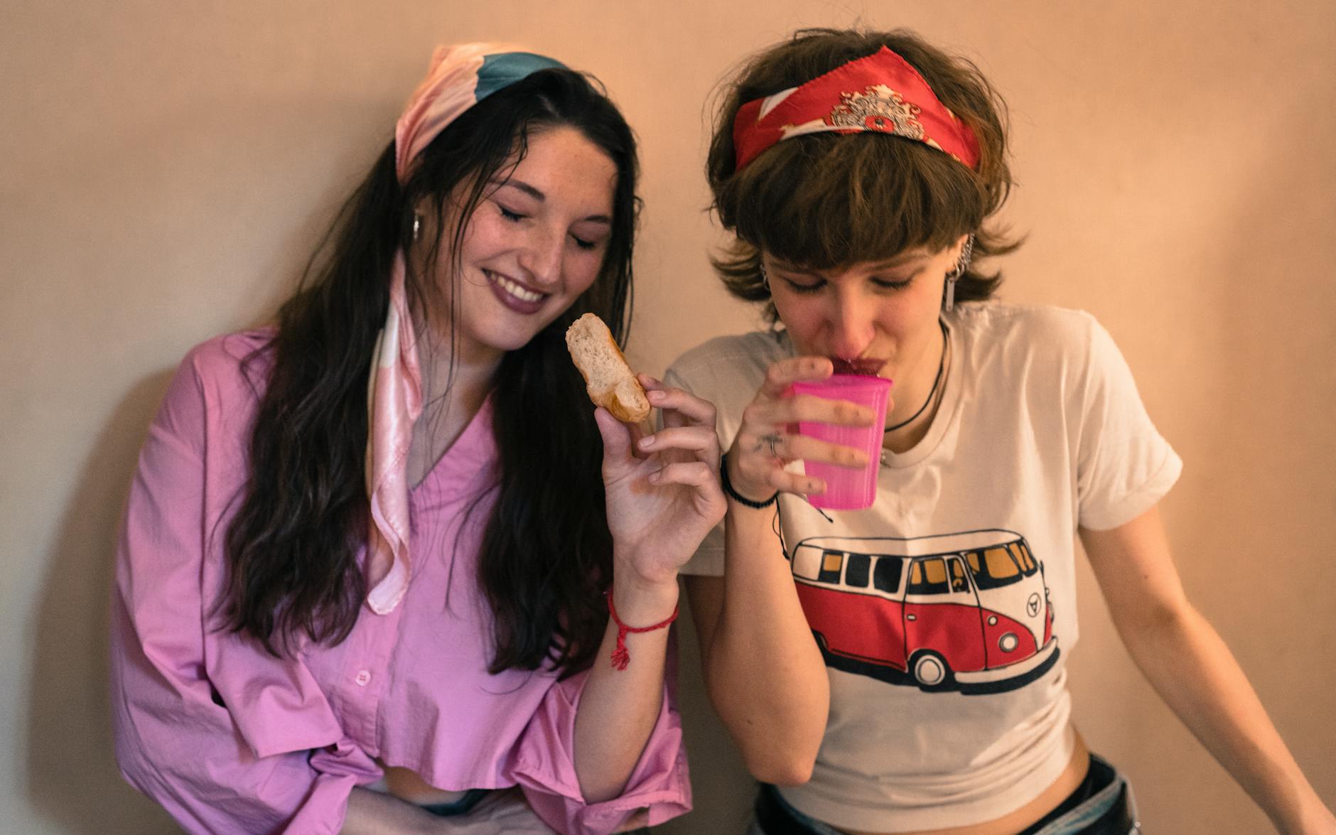 Dwie kobiety w swetrach jedzą i piją razem przy stole indoors