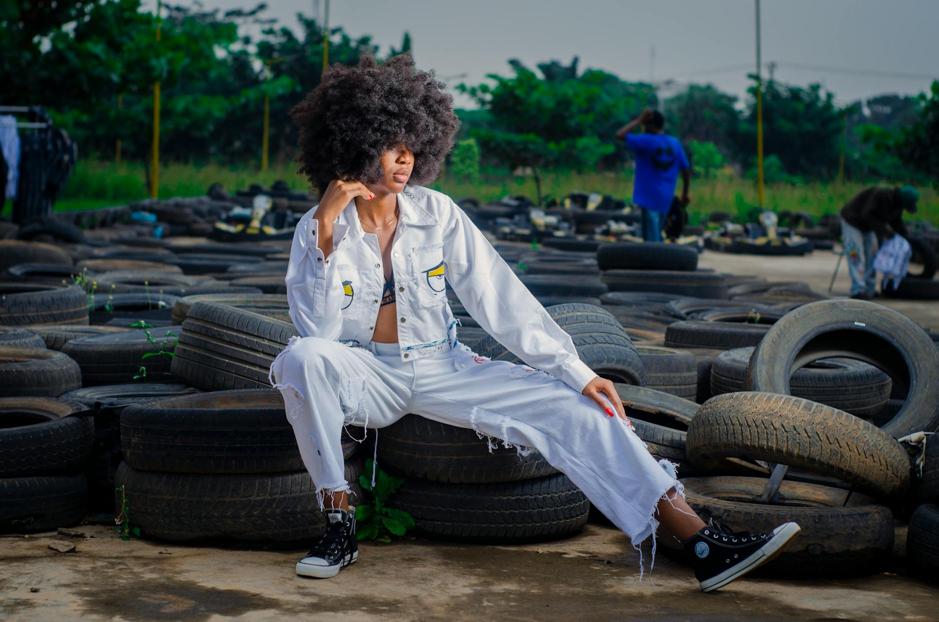 Kobieta w białym denimie siedzi na starych oponach na zewnątrz