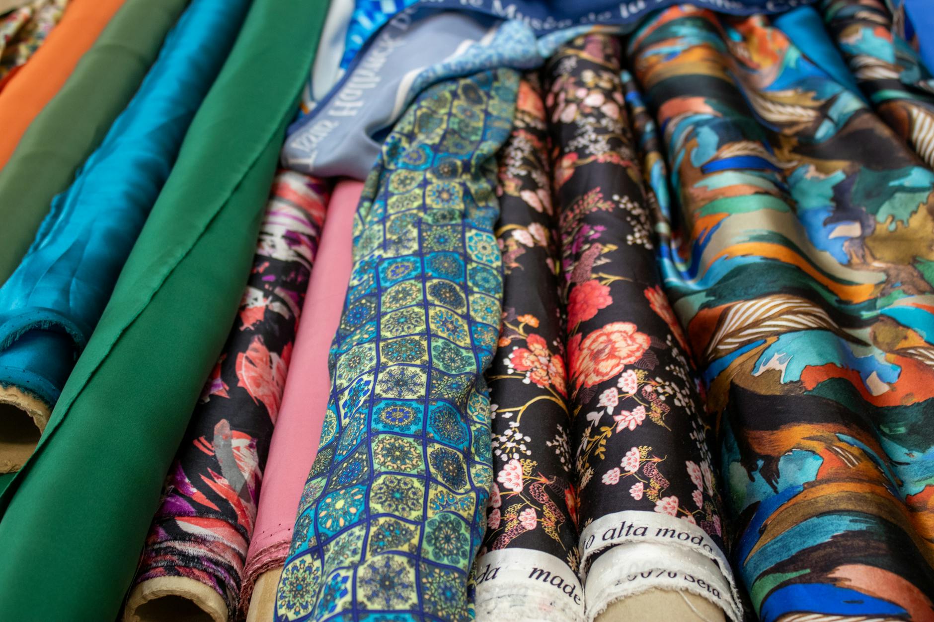Rulony tkanin z różnymi kolorowymi wzorami i fakturami