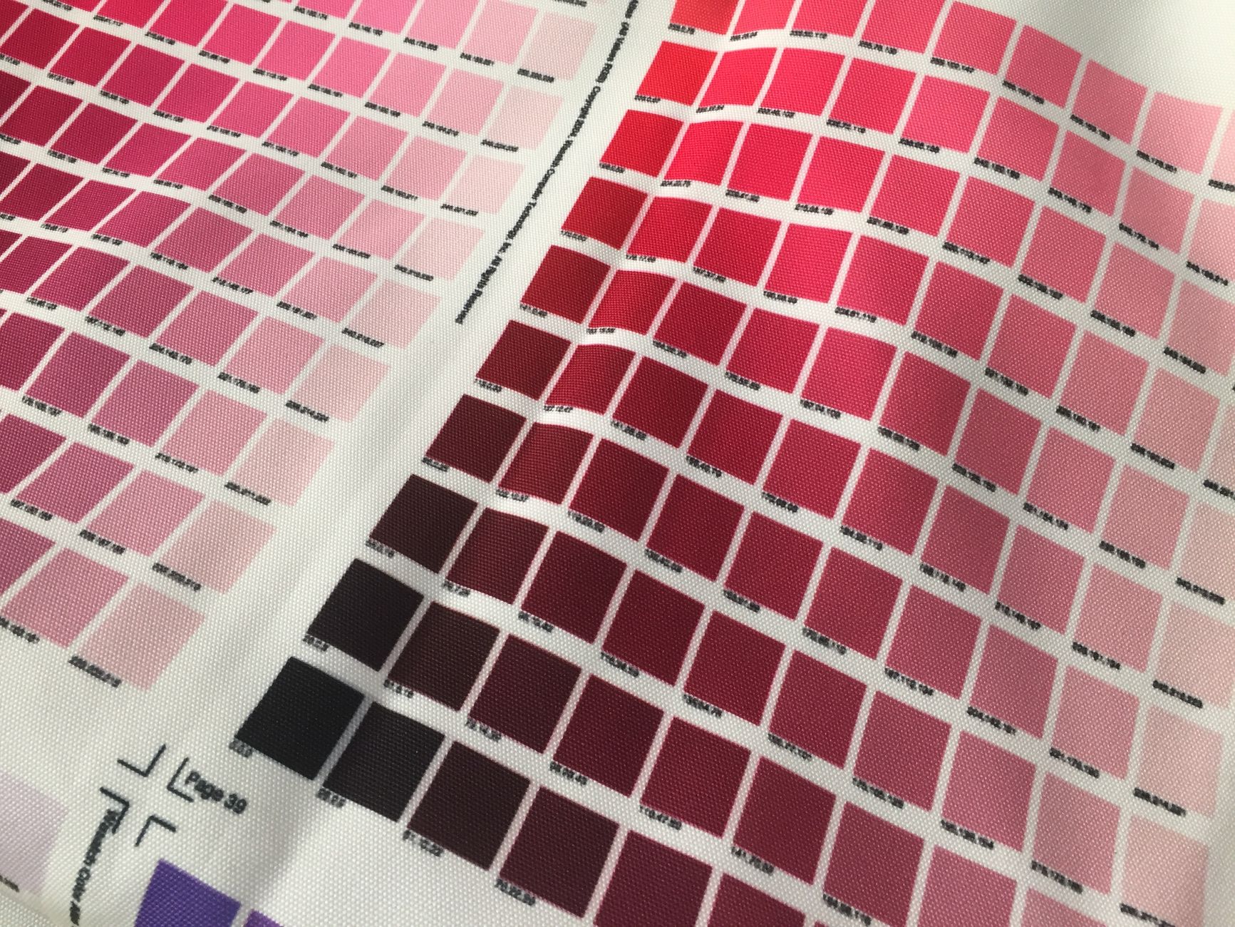 Próbki różowych i czerwonych tkanin do wyboru materiału pod nadruki