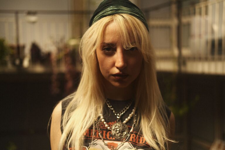 Blondynka w miejskiej stylizacji z retro naszyjnikiem i rockowym pazurem
